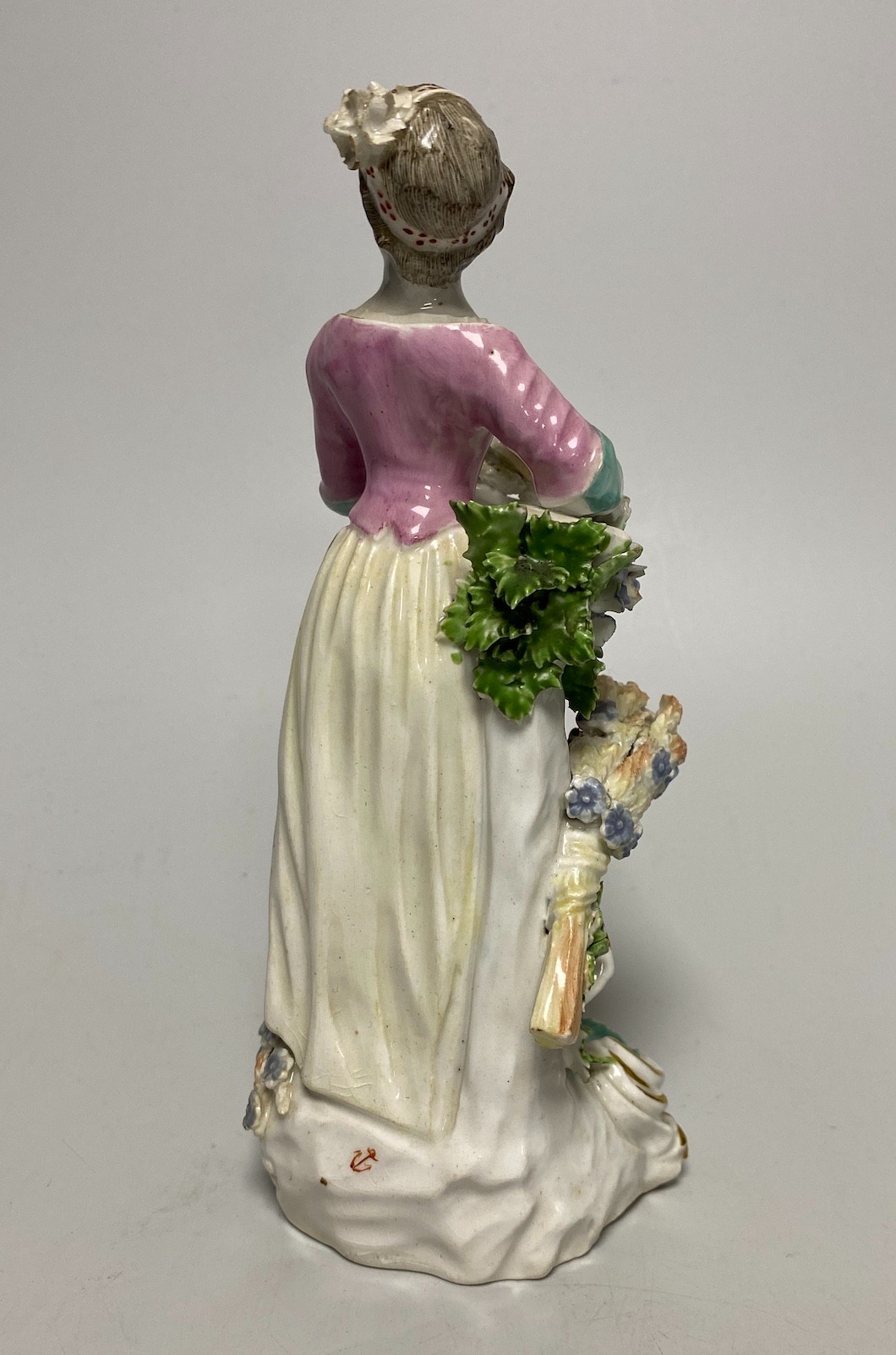 A Derby porcelain figure, emblematic of Summer, modelled as a woman wearing a floral patterned skirt and holding a sheaf of corn, patch marks and red anchor mark, 18th century, 19cm high